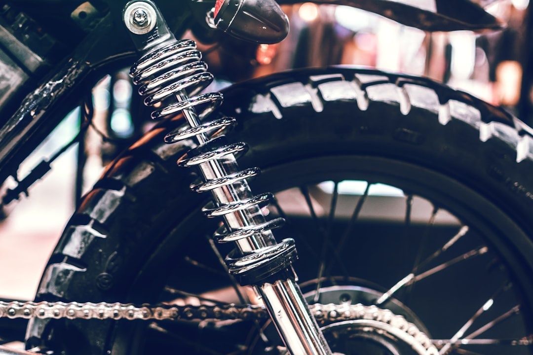 Close-up of a motorcycle rear shock, tire, chain, and wheel