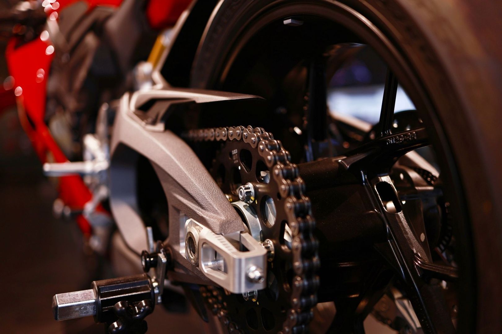Close-up of a motorcycle chain, rear sprocket, and swingarm assembly